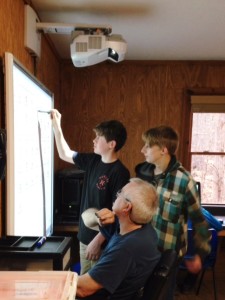 boys boarding school student writes on one of the smart boards